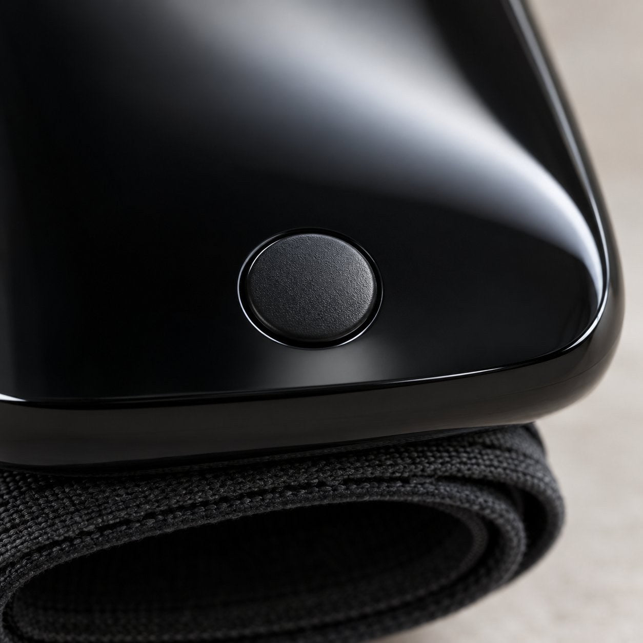 Macro of the single round domed button on the glossy black face of the Pomence wrist blood pressure monitor