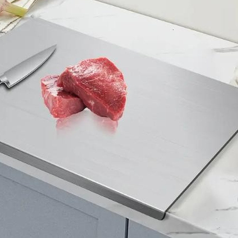 Raw steak resting on the stainless steel chopping board