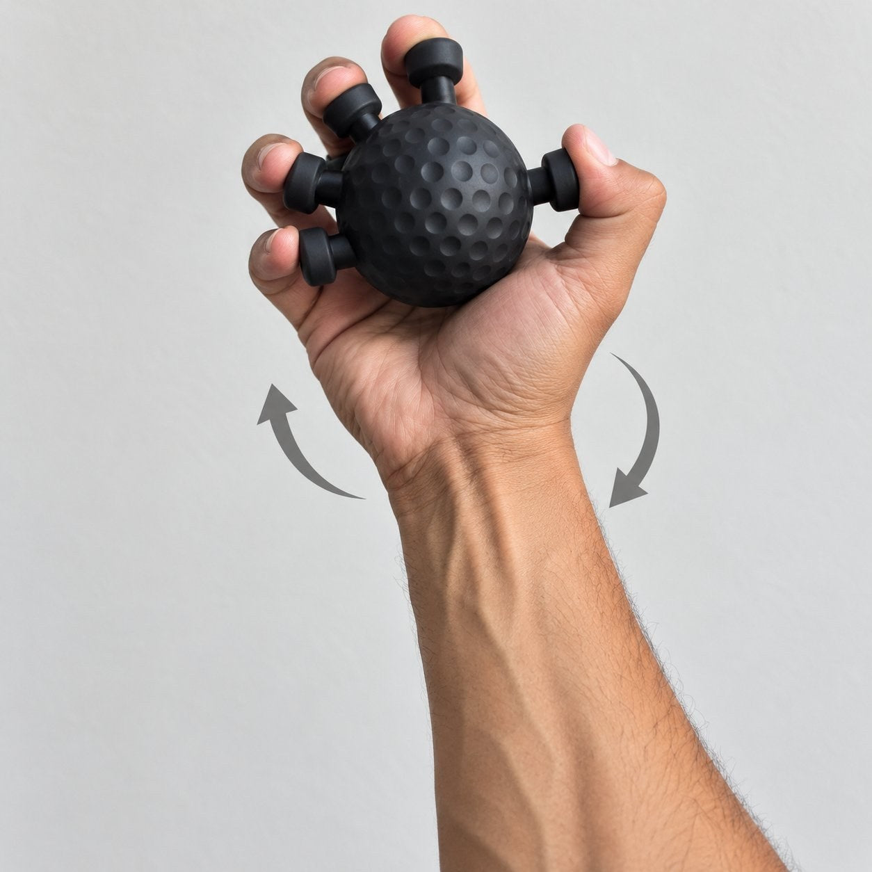 An adult hand rotating the matte black Pomence Forearm Grip Trainer Ball, wrist turning with the fingertips still hooked over the pegs