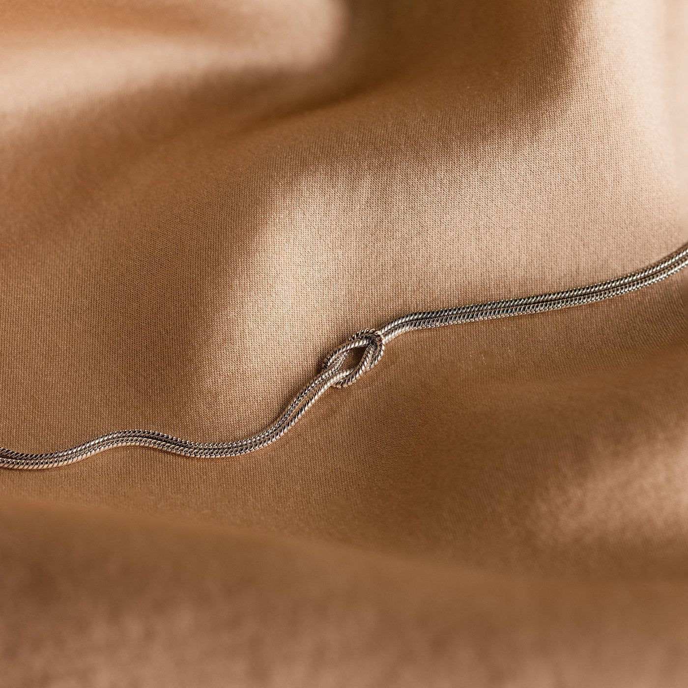 Macro of the two parallel strands of coil-textured snake chain on the Pomence Forever Knot Bracelet in cool steel-silver tone