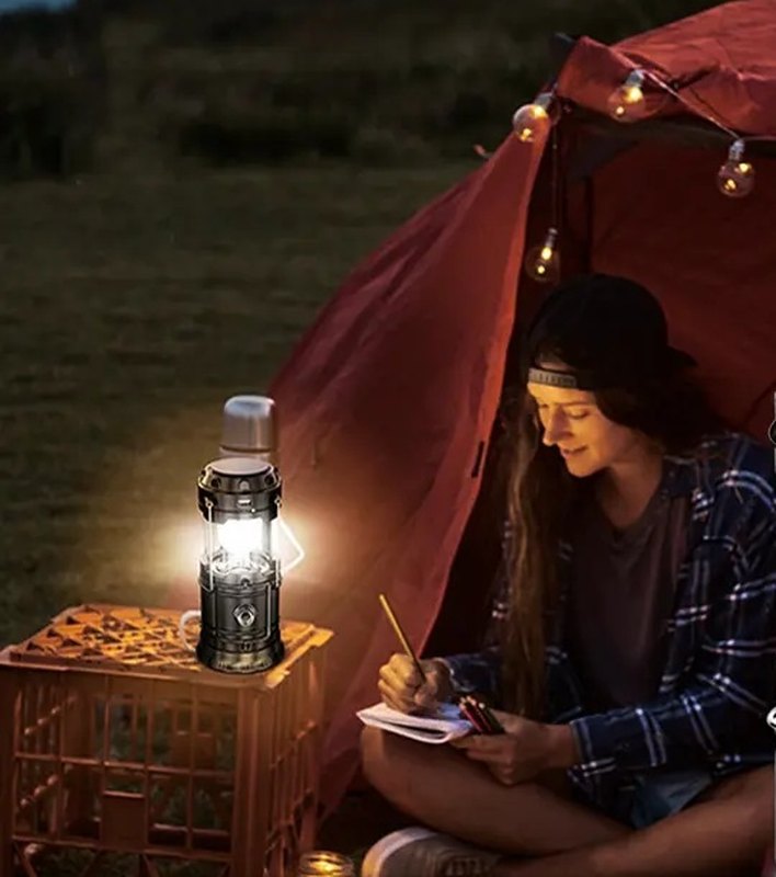 A woman writing in her tent at night by the light of the lantern