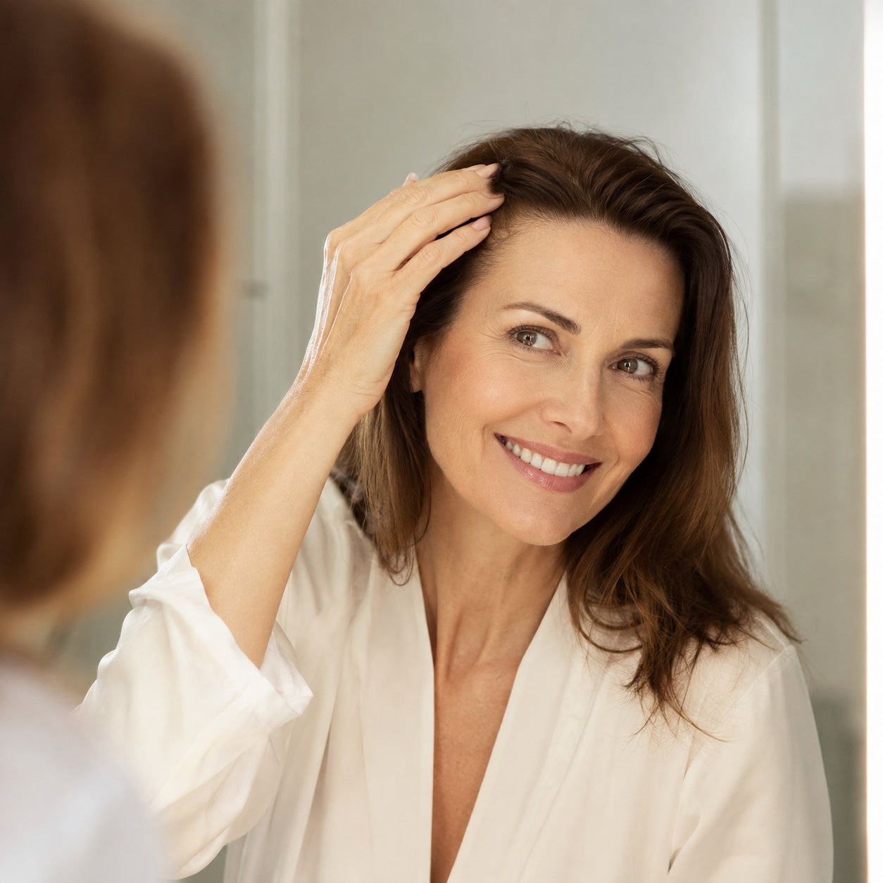Woman smiling at her newly colored, gray-free hairline