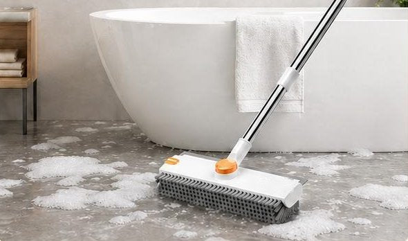 The Pomence 3-in-1 Floor Scrub Brush scrubbing a soapy tile floor beside a bathtub
