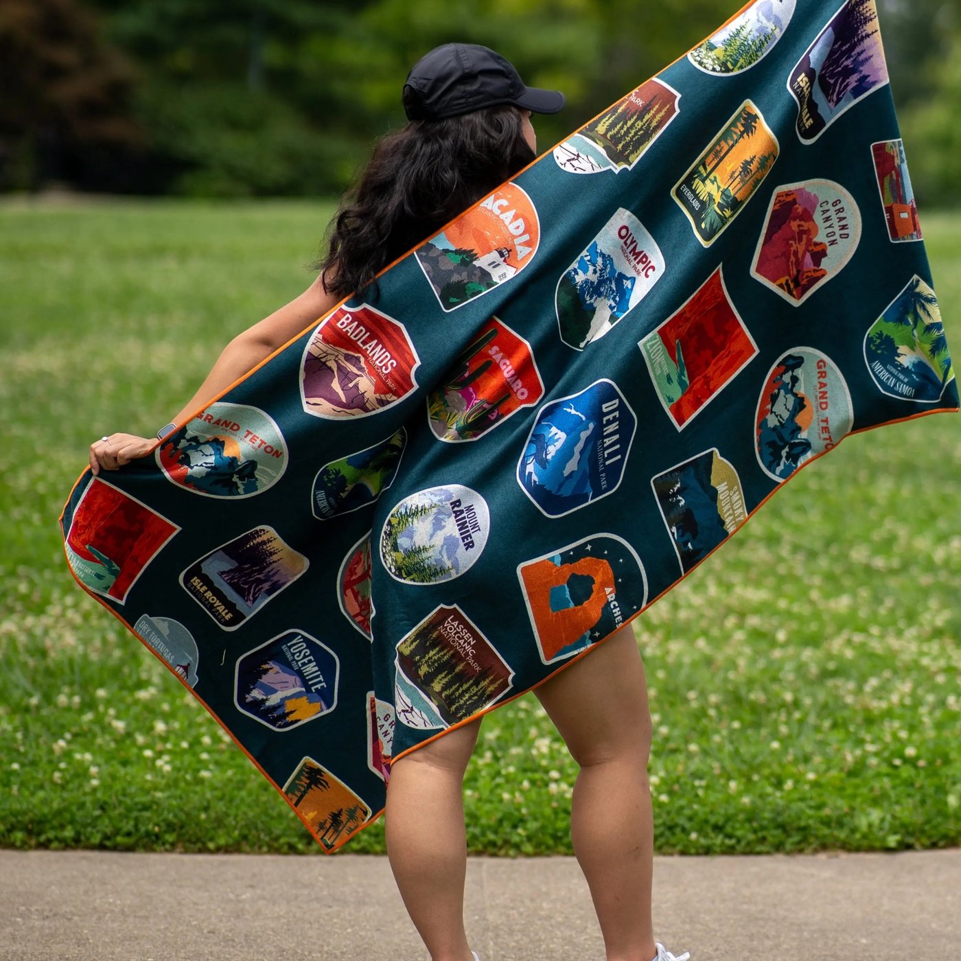 A woman holding the Pomence Car Seat Cover Towel open outdoors like a beach towel