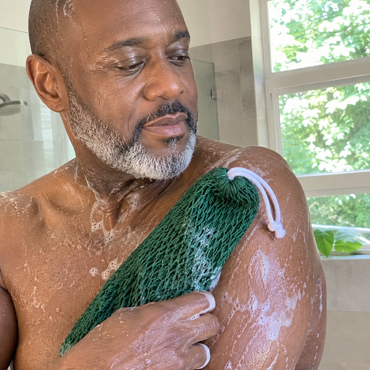 Man scrubbing his shoulder with the green net sponge