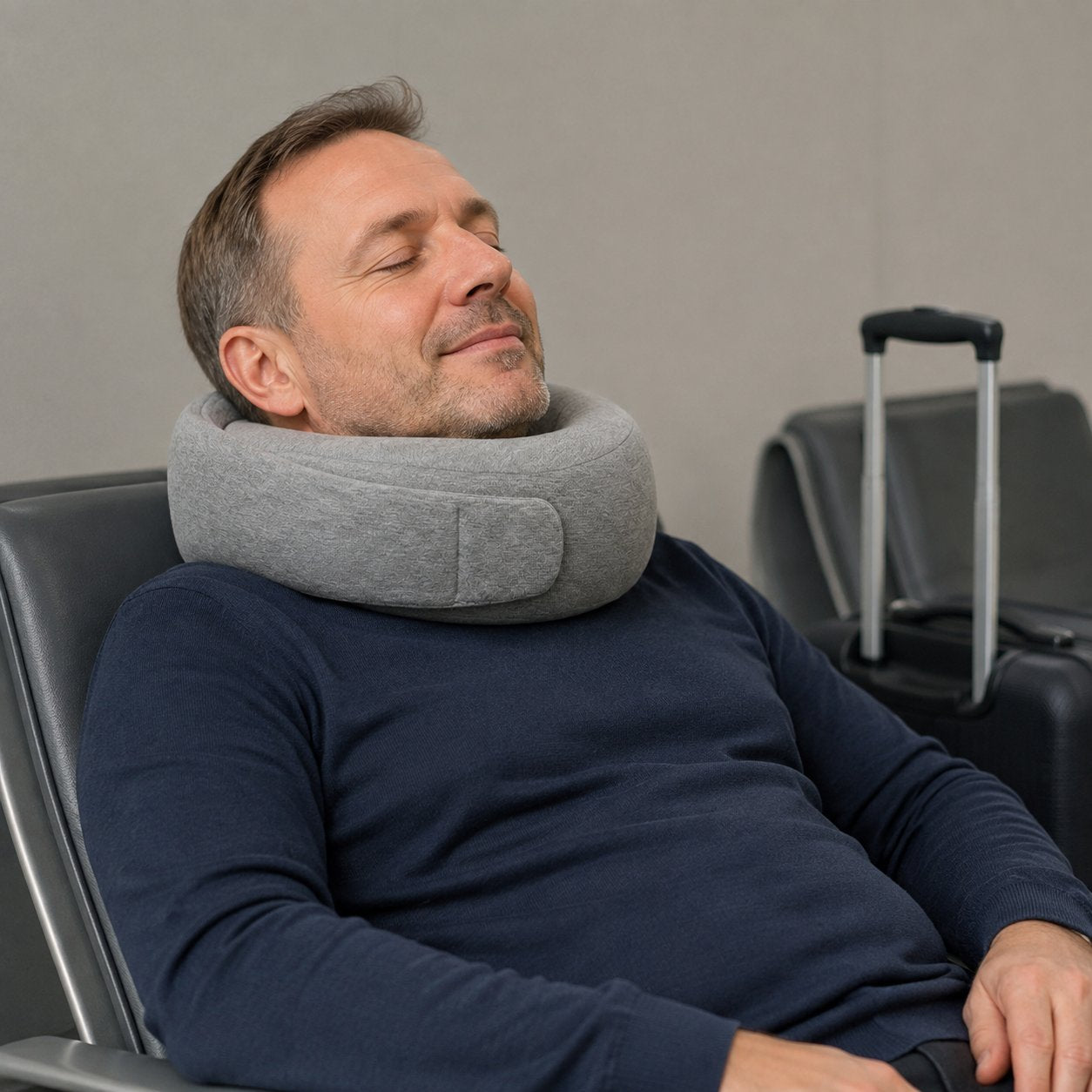 A relaxed traveler resting in an airport lounge chair wearing the Pomence Wrap Travel Neck Pillow