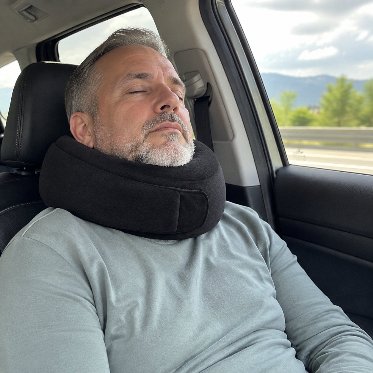 Man dozing in a car passenger seat wearing the Pomence Wrap Travel Neck Pillow
