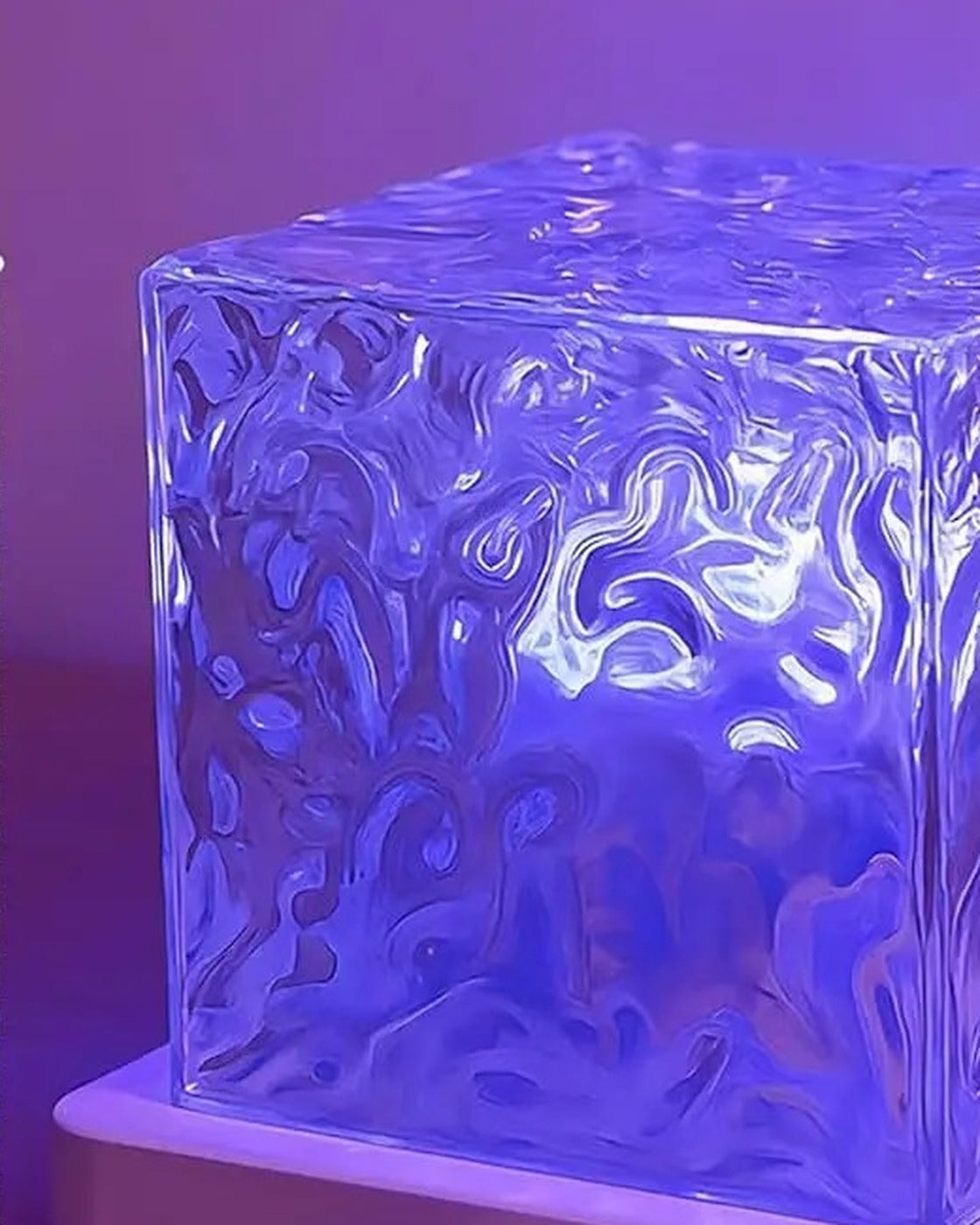 Close view of the crystal cube lamp lit in violet on its white base