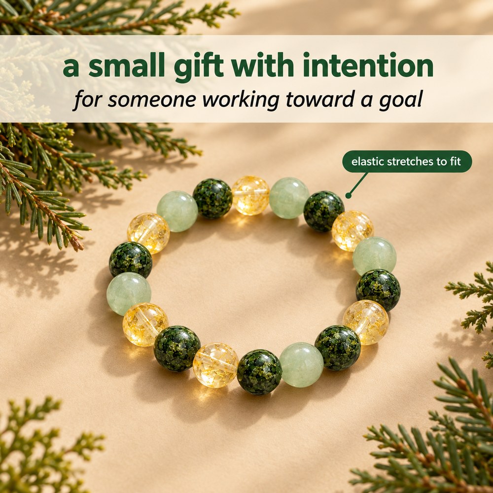 The Pomence Three Stone Abundance Bracelet staged on warm beige with evergreen sprigs