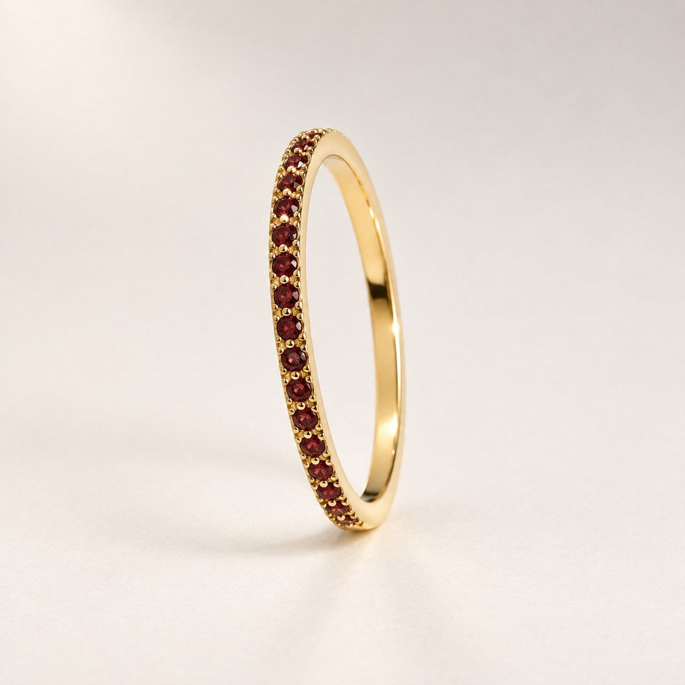 The Pomence Birthstone Stacking Ring alone, a thin gold tone band with a row of red garnet colored stones