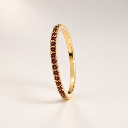 The Pomence Birthstone Stacking Ring alone, a thin gold tone band with a row of red garnet colored stones