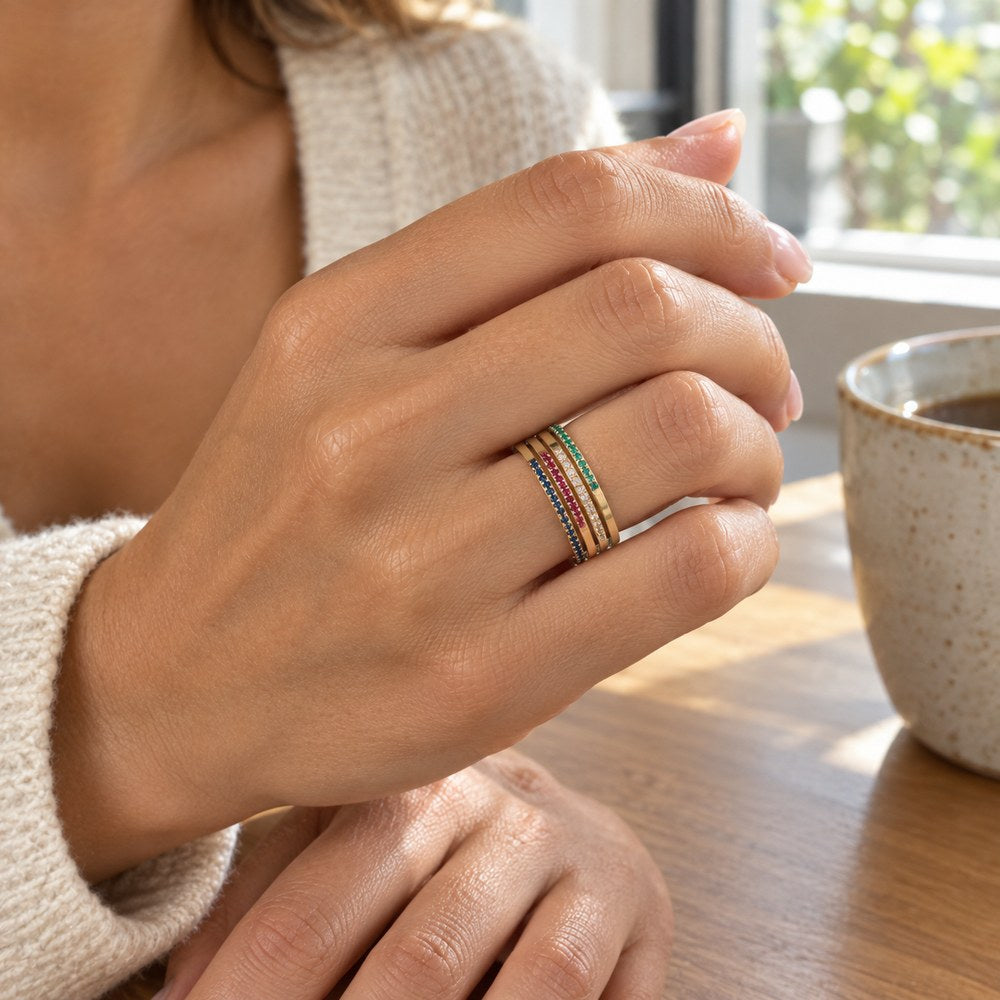 A hand held up wearing four Pomence Birthstone Stacking Rings stacked together on one finger