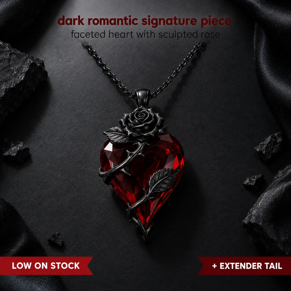 Pomence Blood Rose Necklace flat lay on black, a faceted blood red crystal heart pendant with a sculpted dark gunmetal rose and a thorned stem with two leaves on a fine gunmetal cable chain