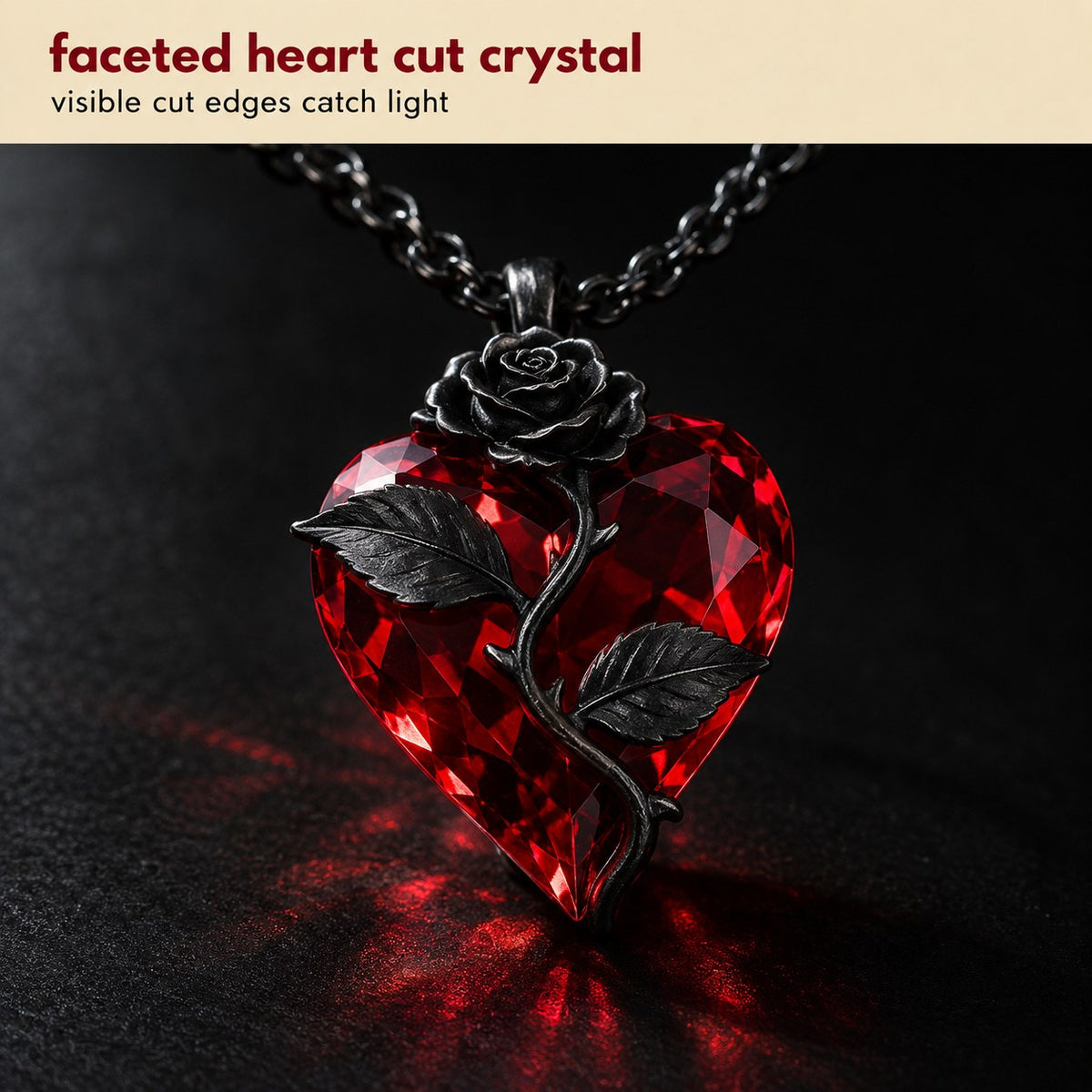 Macro of the Pomence Blood Rose Necklace pendant, the faceted blood red crystal heart with its cut edges, the sculpted gunmetal rose and the thorned stem with two leaves