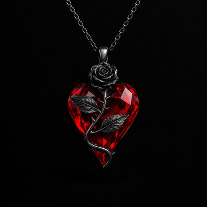 The Pomence Blood Rose Necklace in Black, alone on a near black background, faceted red crystal heart with a dark gunmetal rose and thorned stem