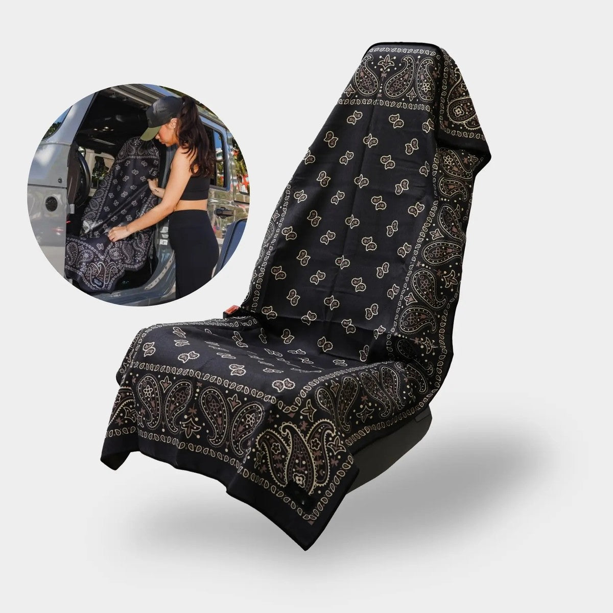 The Pomence Car Seat Cover Towel in Black Paisley over a car seat, and a woman slipping it on