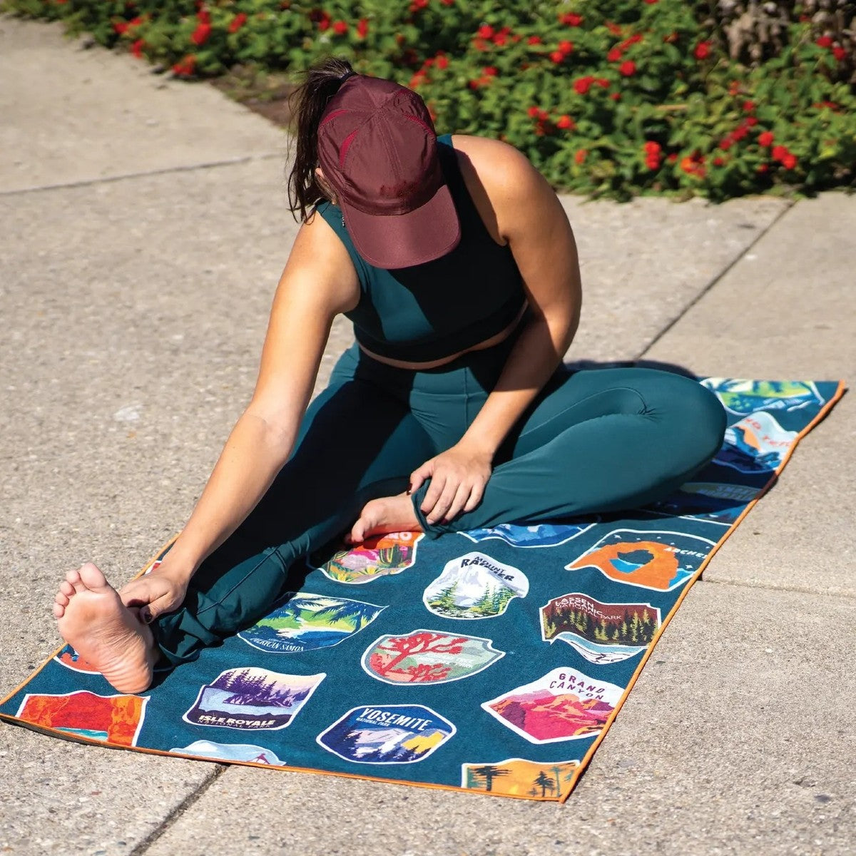 A woman stretching on the Pomence Car Seat Cover Towel laid out as a yoga towel