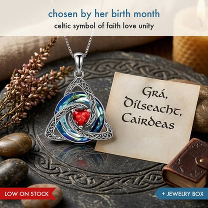 Pomence Birthstone Celtic Knot Necklace, a silver tone open work trinity knot pendant with a heart shaped red birthstone crystal at its center