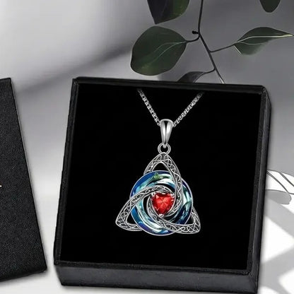 The Pomence Birthstone Celtic Knot Necklace laid in its plain jewelry box