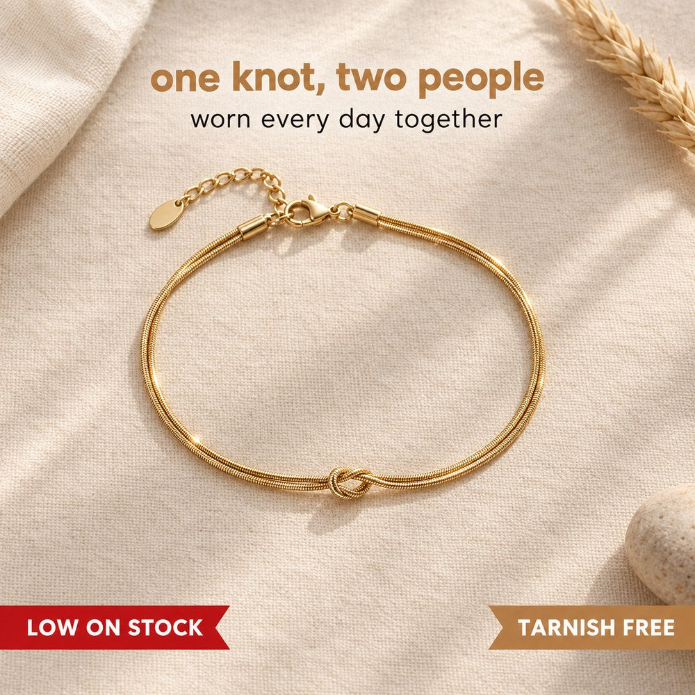 Flat lay of the Pomence Forever Knot Bracelet in warm 18k-gold tone, the single love knot at the center front with the eye of the knot open