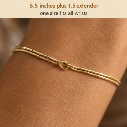 Macro of the two parallel coil-textured snake chain strands and the single love knot of the Pomence Forever Knot Bracelet in warm 18k-gold tone