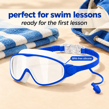 Pomence Kids Swim Goggles laid out beside a folded beach towel and an open swim bag, ready for the first lesson