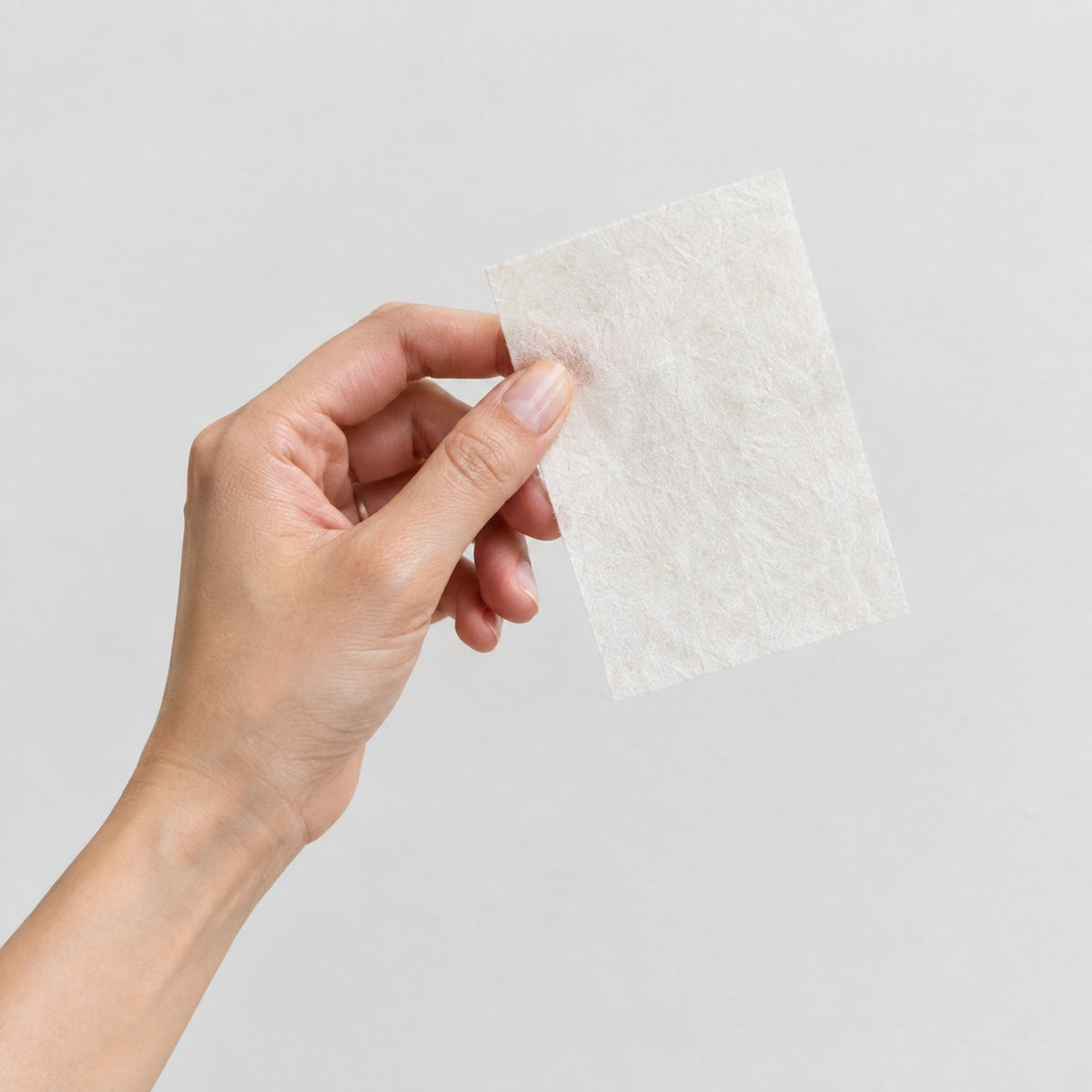 Holding up a single Pomence Laundry Detergent Sheet
