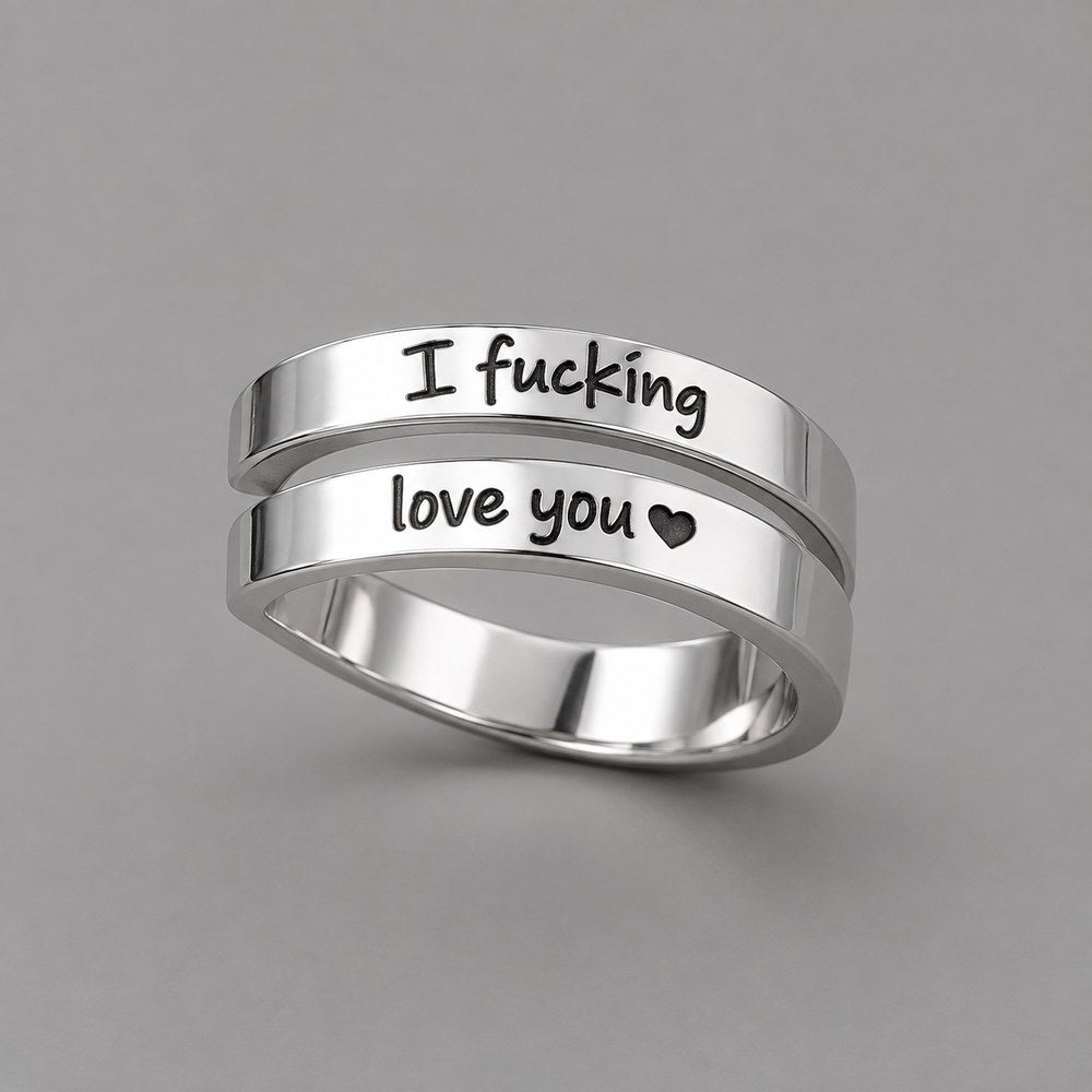 The Pomence I F♡cking Love You Ring alone in three-quarter view on a warm grey ground