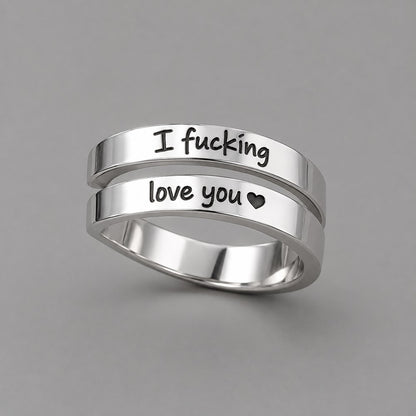 The Pomence I F♡cking Love You Ring alone in three-quarter view on a warm grey ground