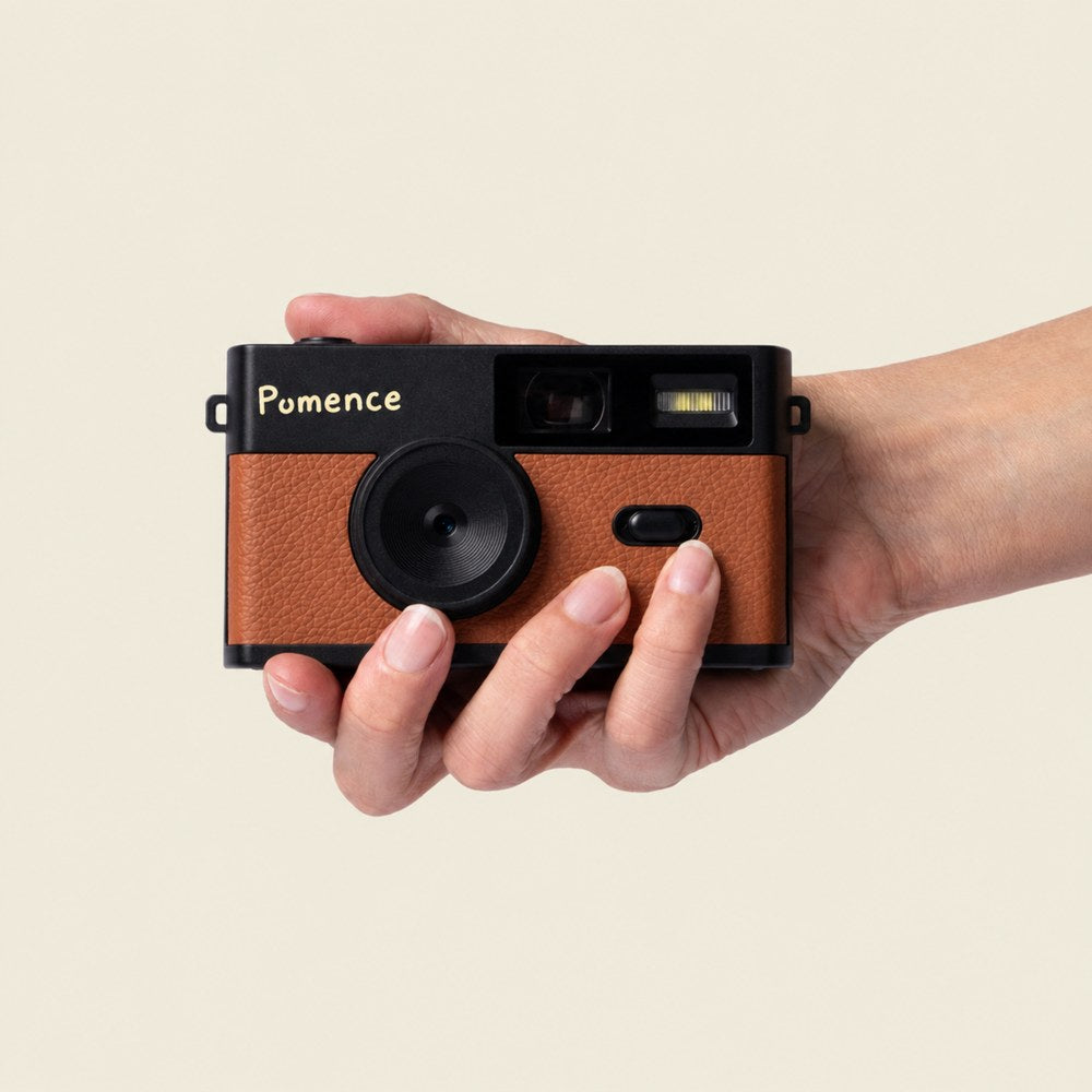 A hand holding the tan Pomence Mini Retro Camera