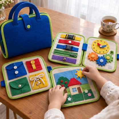 Over-the-shoulder view of a small pair of hands at a wooden table working one of the four detachable felt pages of the Pomence Montessori Busy Board, the other three laid open beside it with a learning clock, turning gears and a velcro picture puzzle