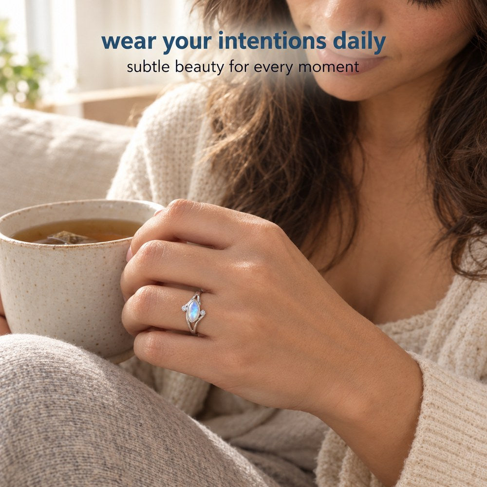 A woman at home holding a mug, wearing the Pomence Moonstone Ring on her ring finger