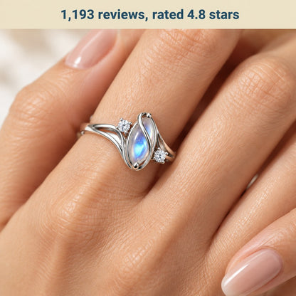 Macro of the Pomence Moonstone Ring worn on a ring finger, showing the marquise stone and the two round CZ accents