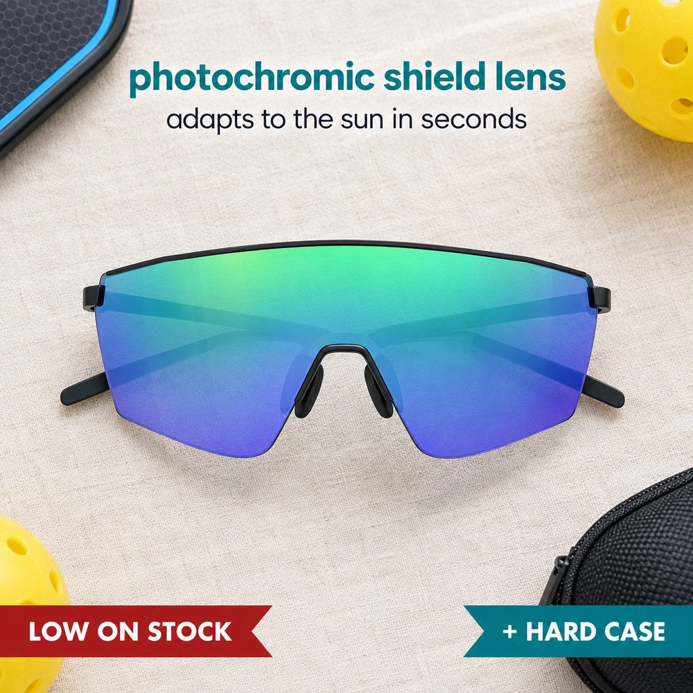 Pomence Photochromic Sport Sunglasses in Blue laid flat with a pickleball paddle and ball