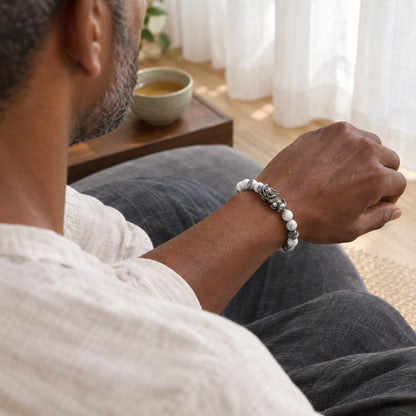 A man seated at a meditation cushion wearing the Pomence Pixiu Wealth Bracelet, the charm visible on the top of his wrist