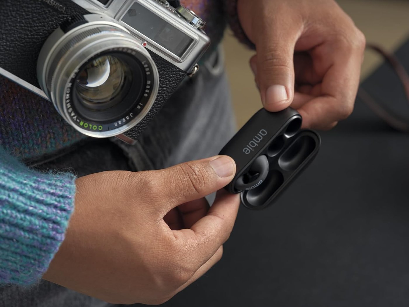 Hand holding the black Ambie charging case