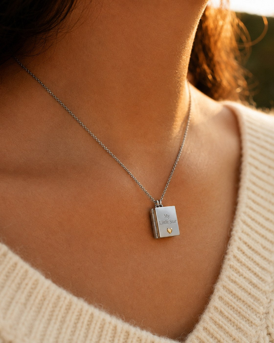 A woman wearing the Pomence My Little Star Book Locket Necklace at her collarbone in soft daylight
