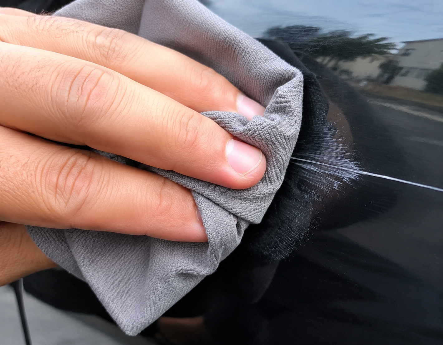 Car Cloth wiping a deep scratch on a black car door