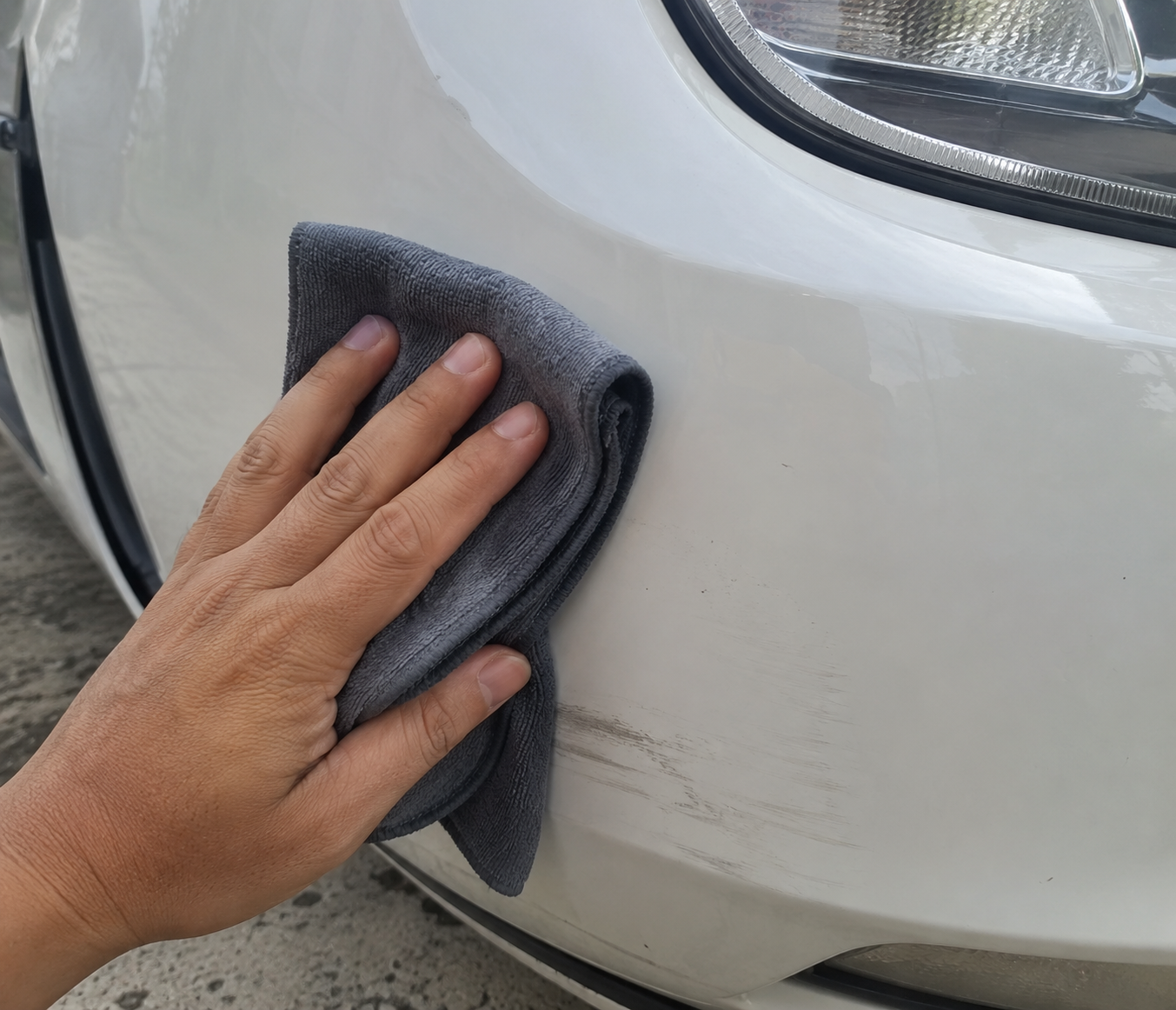 Car Cloth removing a scuff from a white bumper corner