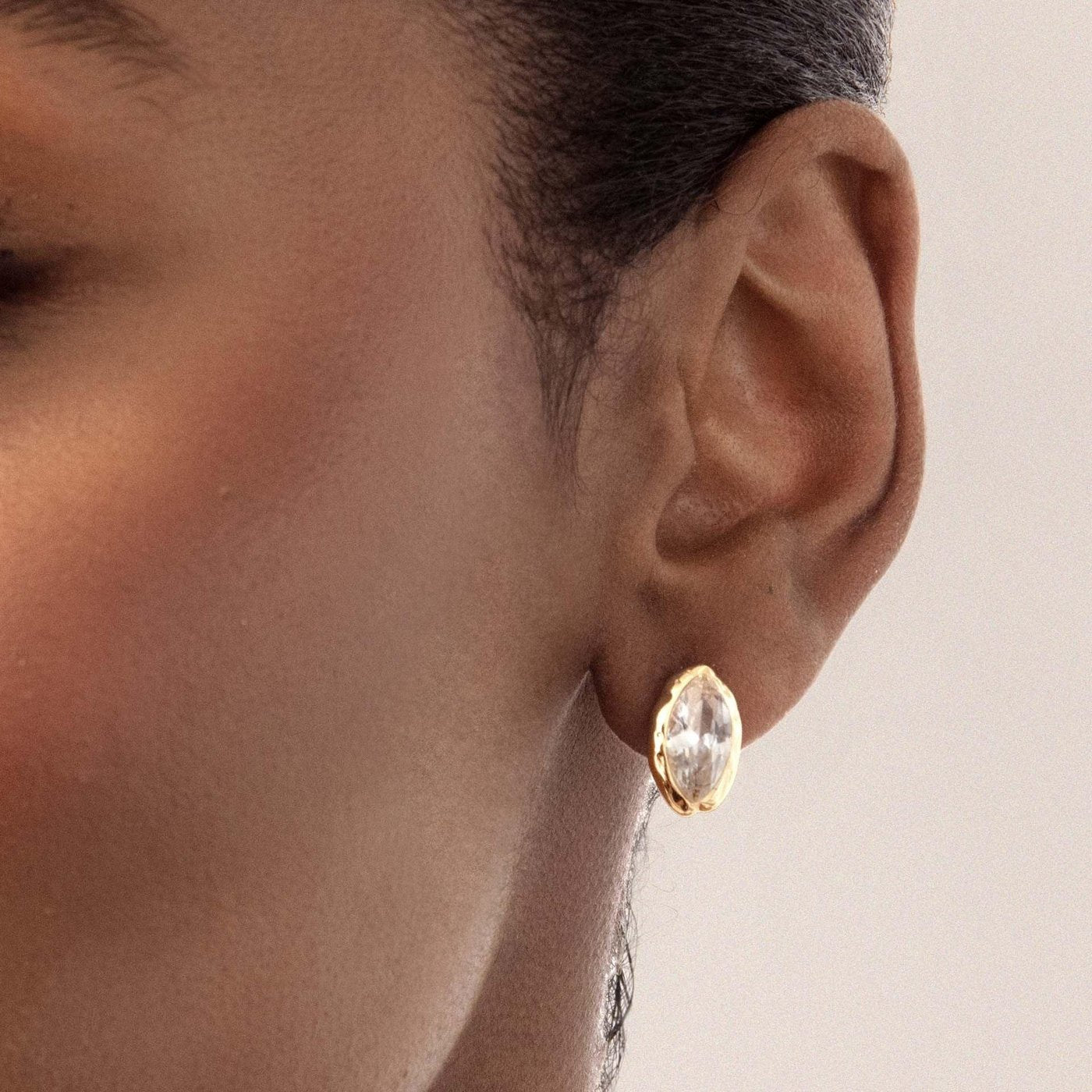 The Pomence Crystal Mini Stud Earrings worn on the lobe, shown for scale against the ear