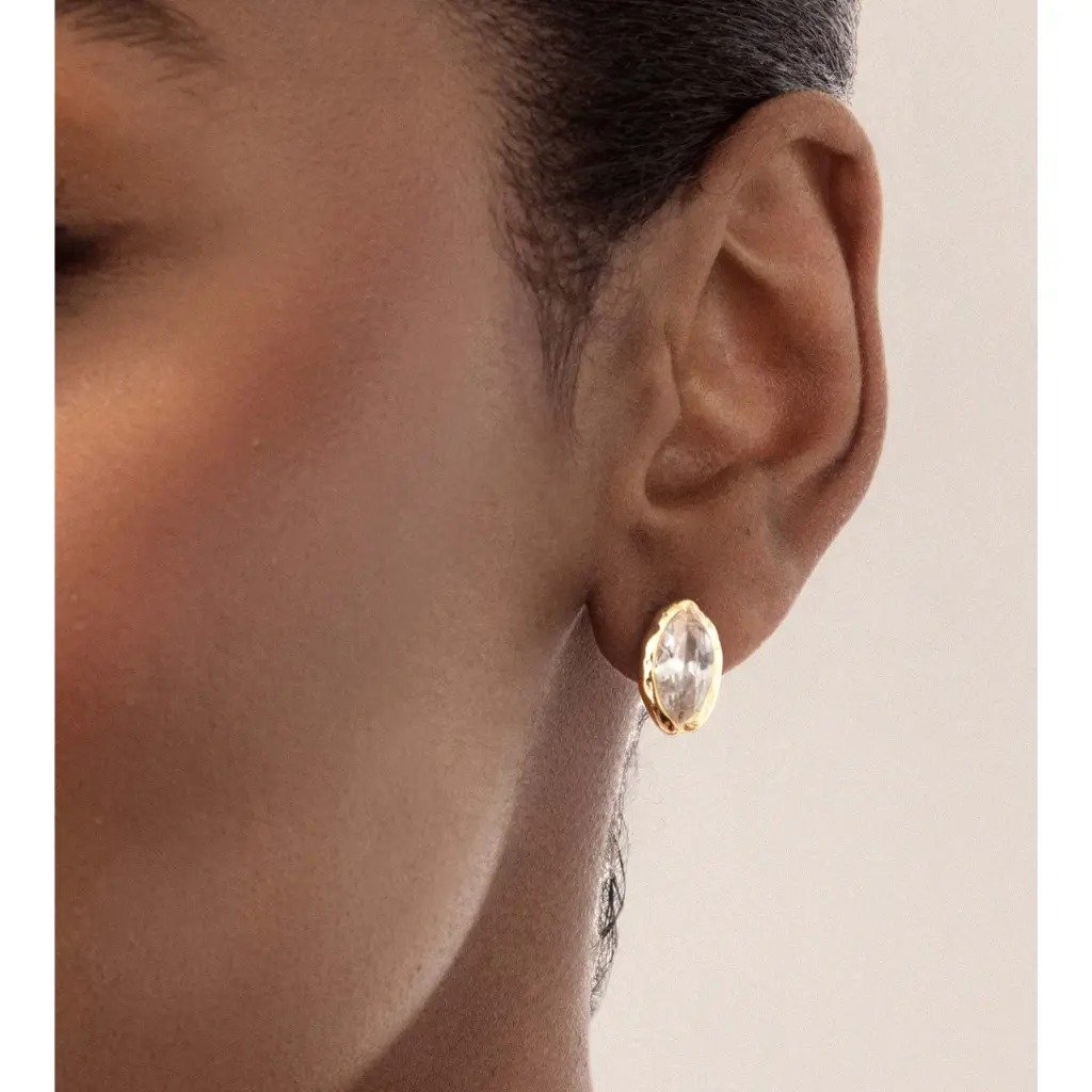 A woman wearing the Pomence Crystal Mini Stud Earrings in clear crystal, close on the ear
