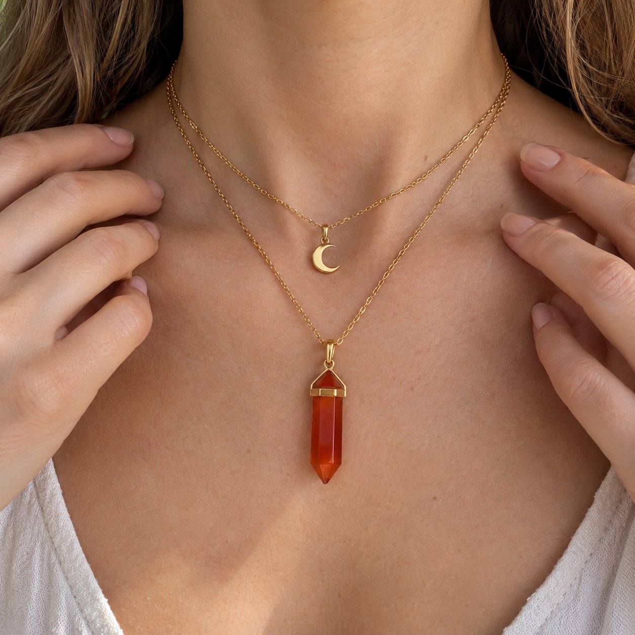 The carnelian point of the Pomence Carnelian Attraction Necklace held up to daylight showing the natural red to orange banding