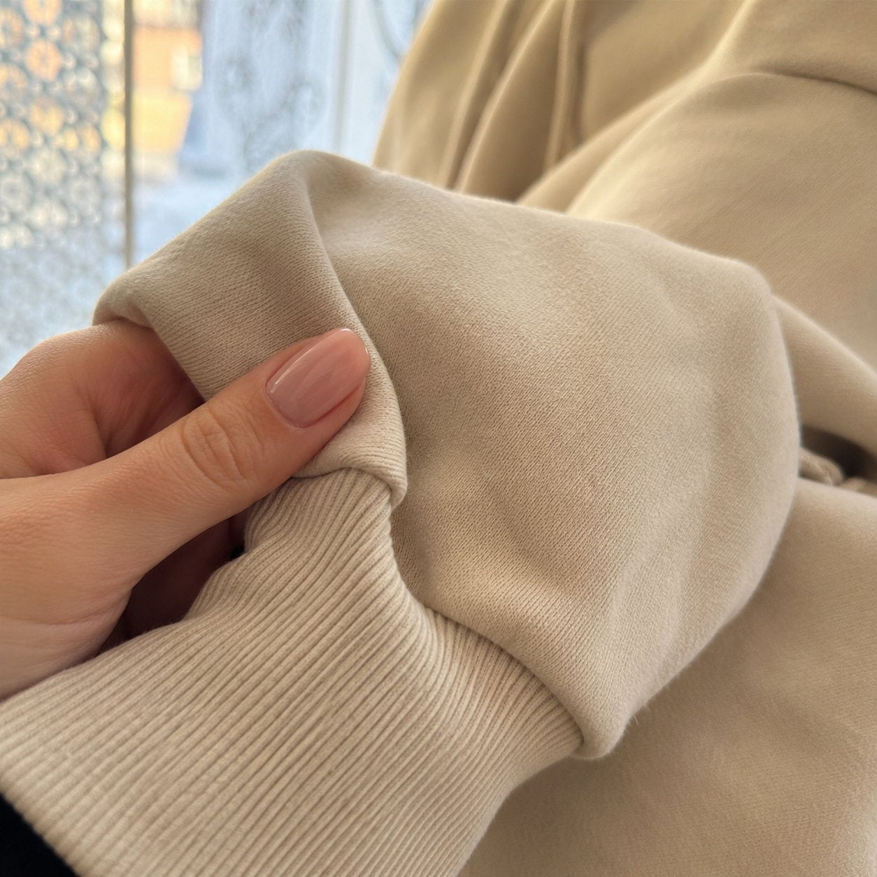 Close-up of the ribbed cuff and soft cotton of the beige sweatshirt