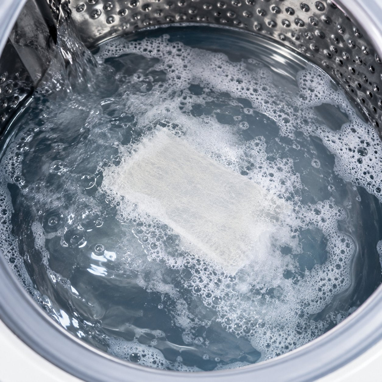 A Pomence Laundry Detergent Sheet dissolving into suds in a washing machine drum