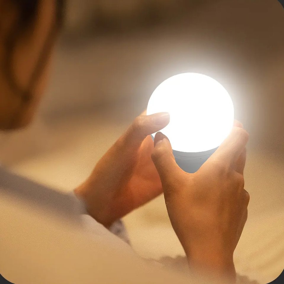 Two hands holding the glowing bulb