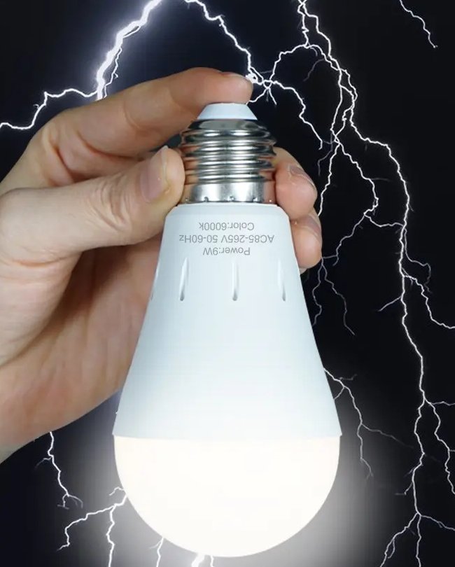A hand holding the lit Pomence rechargeable emergency light bulb during a lightning storm