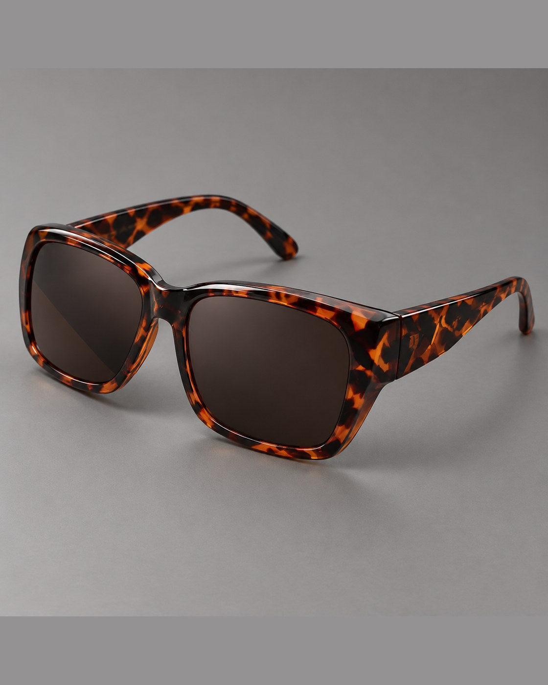 Pomence Fit-Over Sunglasses in Tortoise photographed alone on a warm gray background