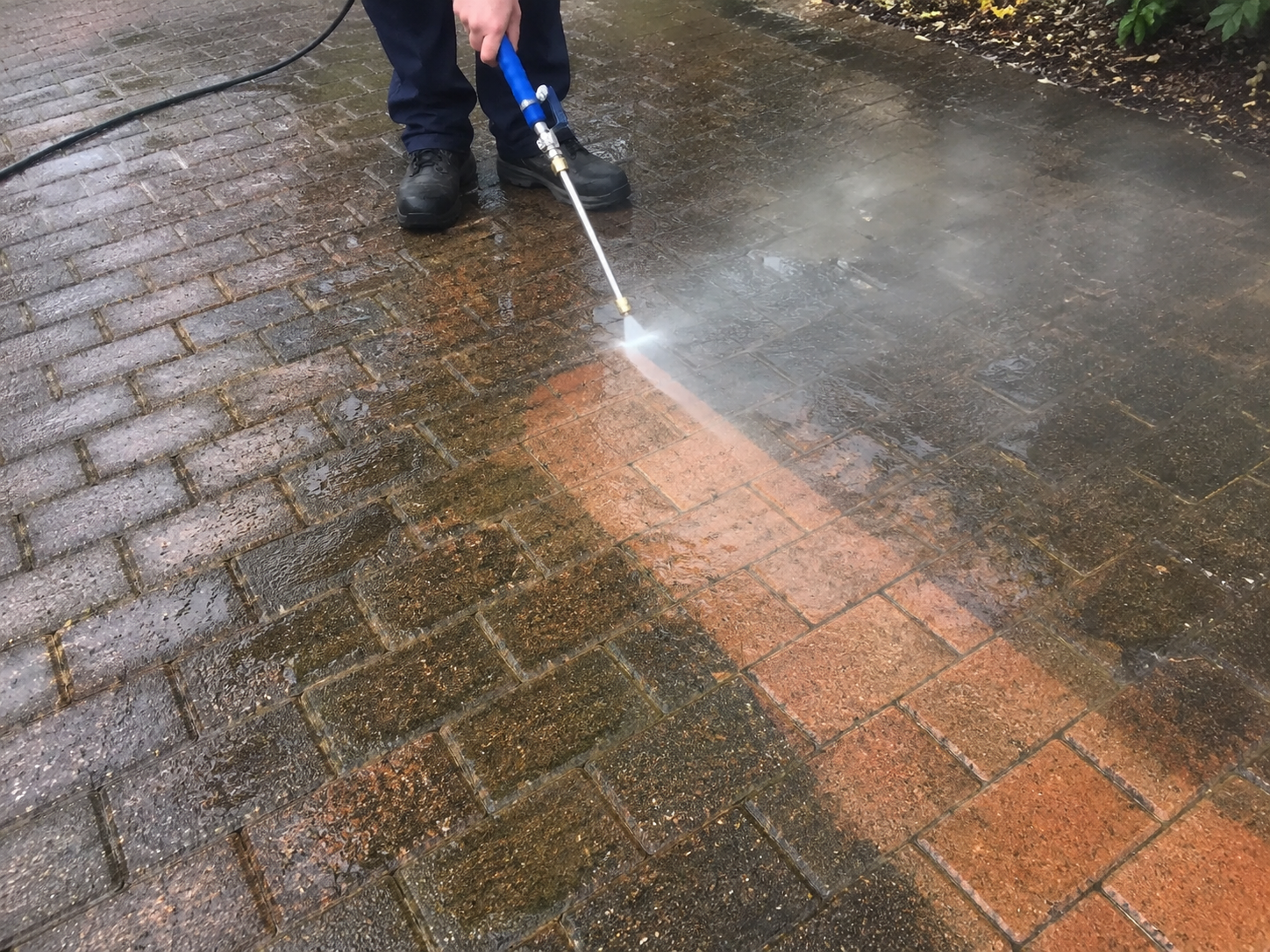 JetHose blasting grime off a brick paver driveway