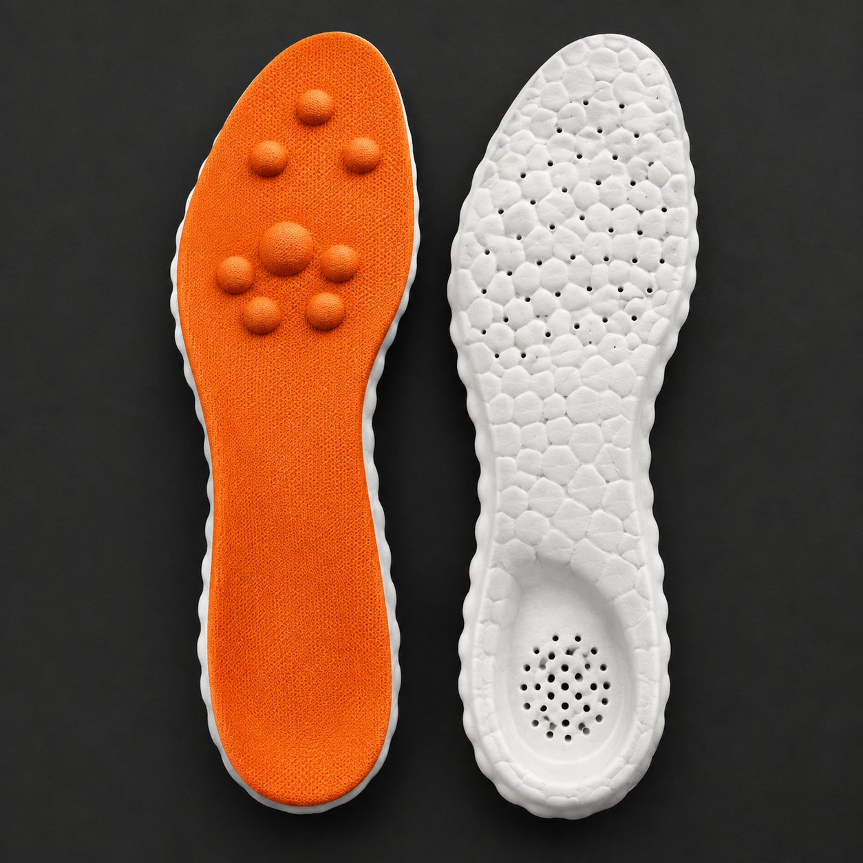 A pair of Pomence Massage Insoles resting beside a work boot and a trainer at the end of a day