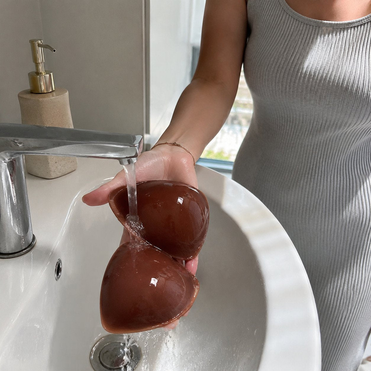 A Pomence bra insert being rinsed under a tap
